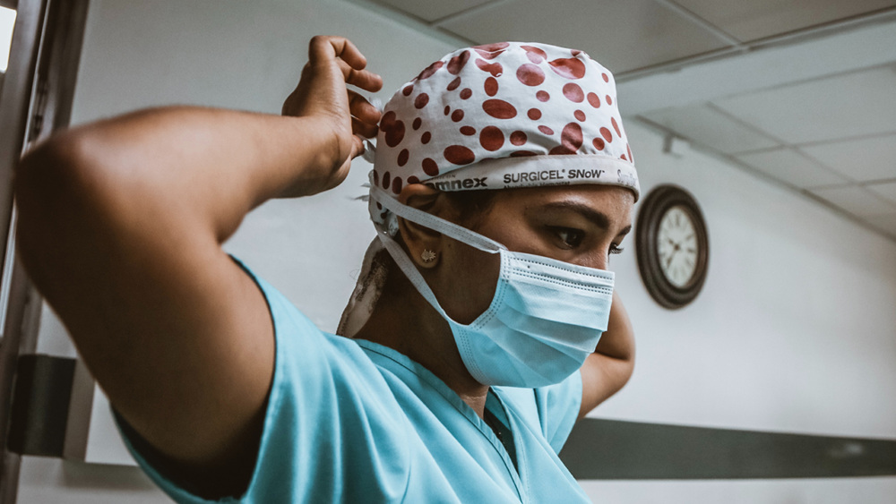 A nurse tightens her PPE in a hospital hallway.